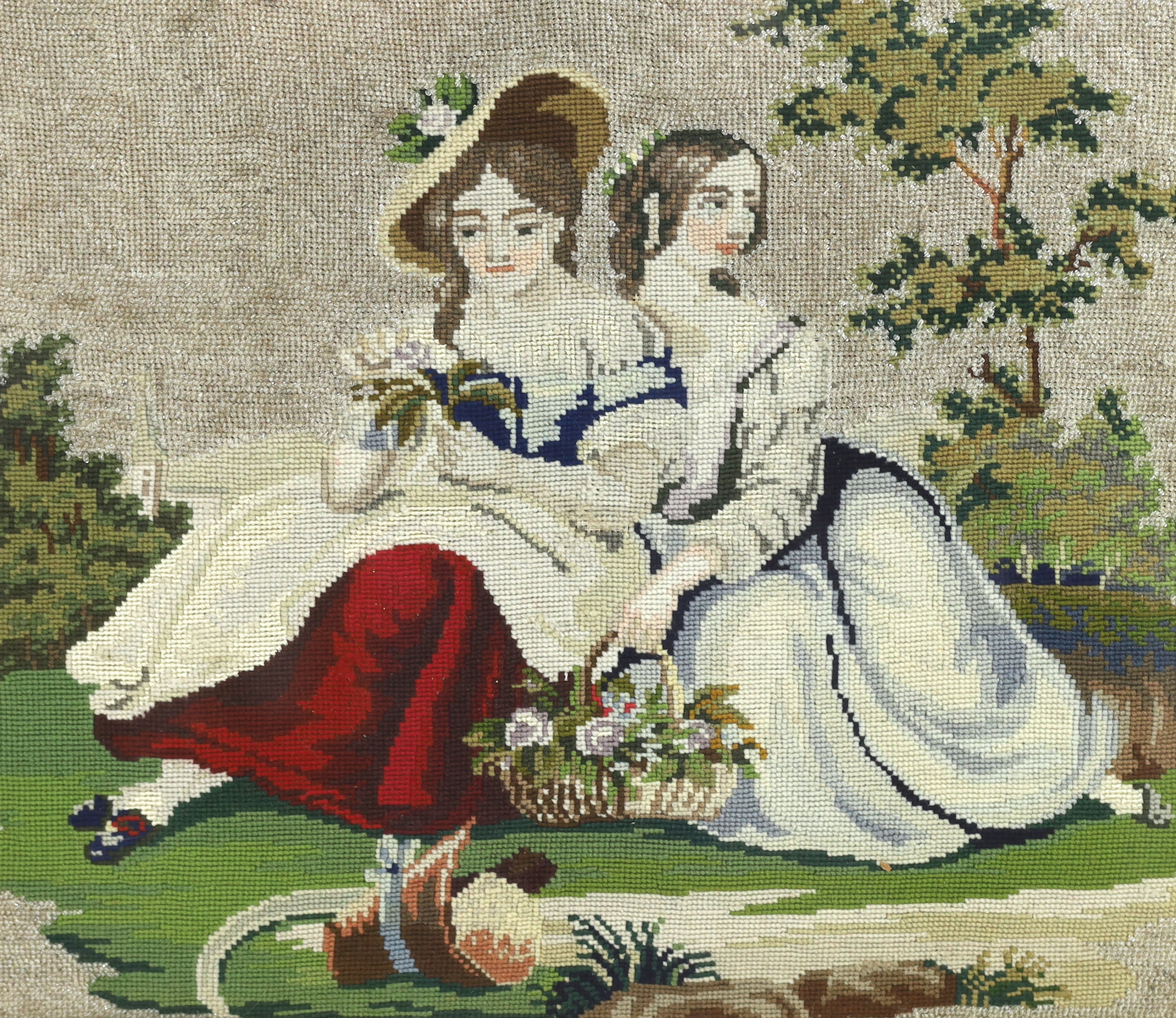 A 19th century maple framed Berlin beadwork embroidery of two young girls, possibly Queen Victoria’s daughters, seated with a basket of flowers in a garden, the sky embroidered with white beads, 49cm wide x 42cm high